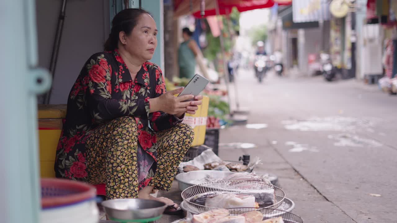 Street Vendor in Asian Market Using Mobile Phone
