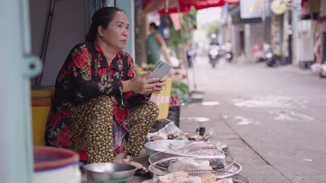 street vendor in asian market using mobile phone