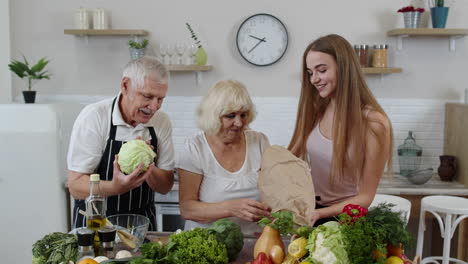 elderly couple in kitchen receiving vegetables from grandchild. raw food healthy eating diet