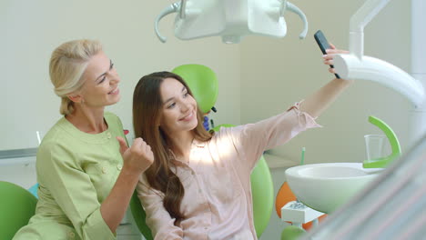 Feliz-Médico-Y-Paciente-Tomándose-Selfie-Juntos.-Mujer-Sonriente-En-La-Silla-Del-Dentista