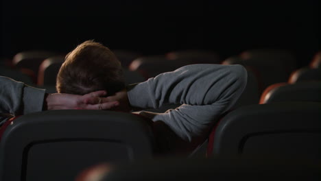 Young-man-relaxing-in-empty-dark-theatre