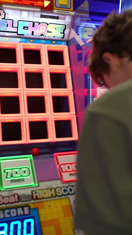 intense gamer focusing intently on beating previously set high score of 9300 during challenging pixel chase arcade game, navigating colorful illuminated grid with precise reflexes and concentration
