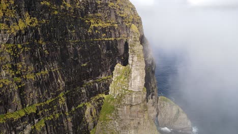 circular drone footage of the witch finger in the clouds at sandavagur on the vagar island in the faroe islands