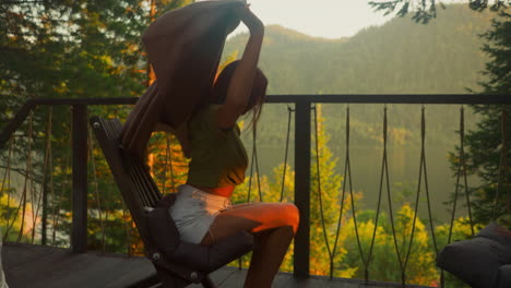 calm woman covered with warm blanket sits enjoying scenic view of pristine and untouched nature on balcony. country house for rent to tourists slow motion