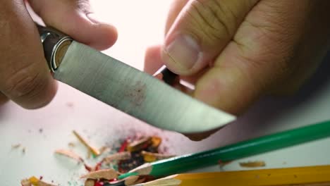 Footage-of-hands-slowly-sharpening-a-pencil-and-some-coloured-pencils-with-a-sharp-knife