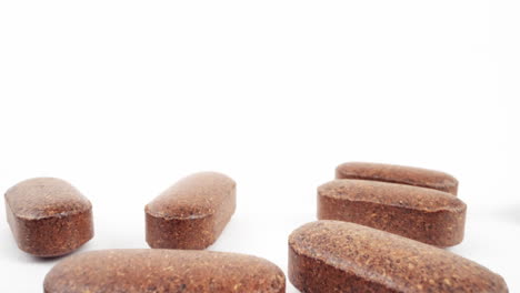 brown nutritional supplement tablets artistically arranged on a pure white background