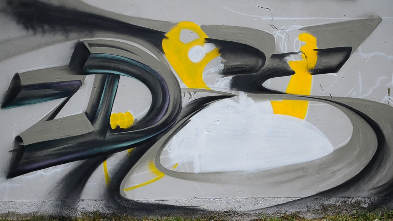 The artist draws graffiti on a fence, abstraction