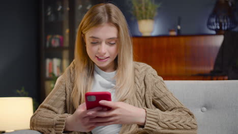 Happy-Young-Woman-Chatting-On-Smartphone-While-Sitting-On-A-Couch-At-Home