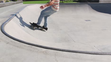 Low-section-of-caucasian-man-riding-and-jumping-on-skateboard-on-sunny-day