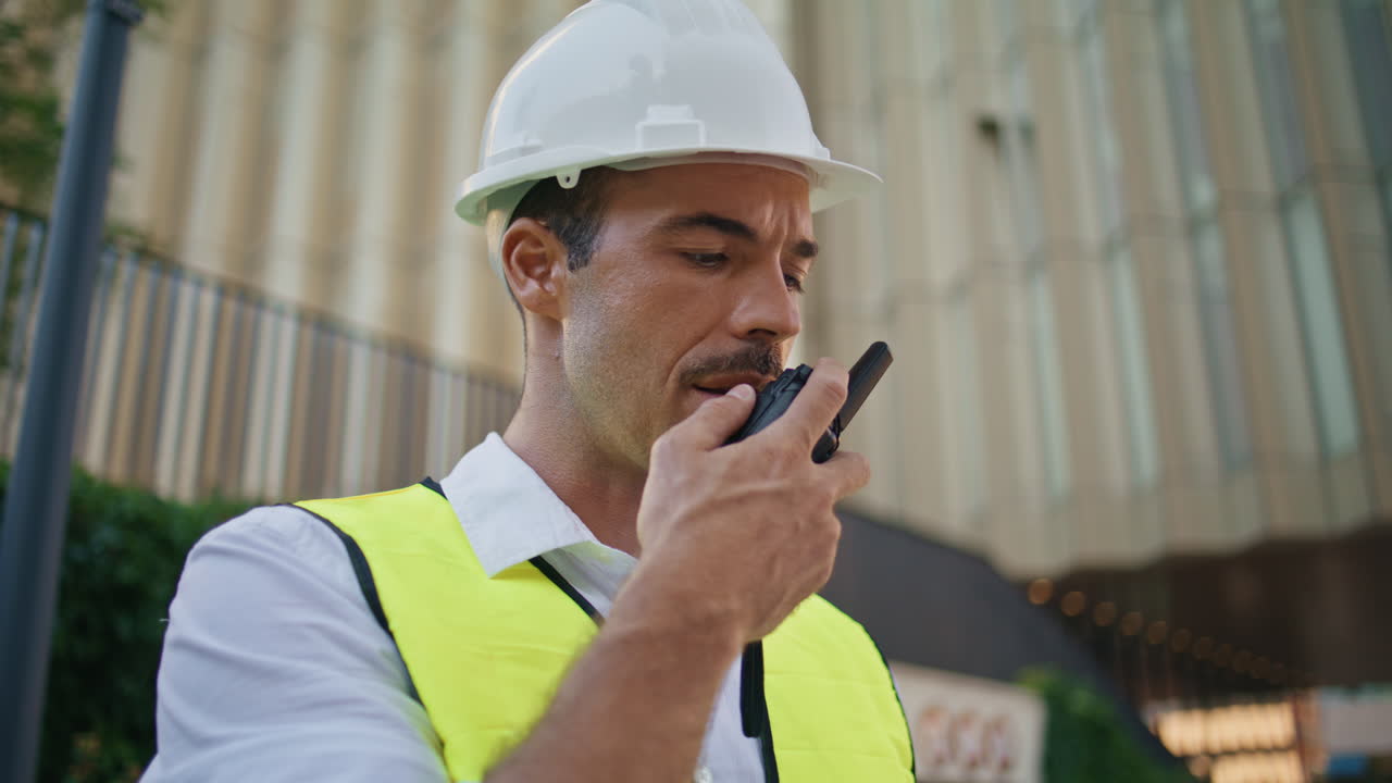 Tanned contractor communicating walkie-talkie summer city closeup. Man talking