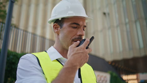 tanned contractor communicating walkie-talkie summer city closeup. man talking