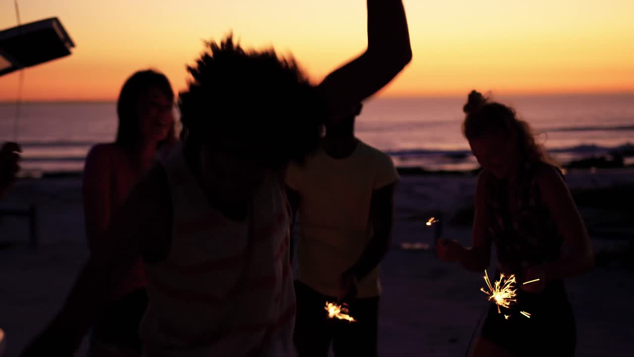 Young adult friends having fun on the beach at night with sparklers 4k