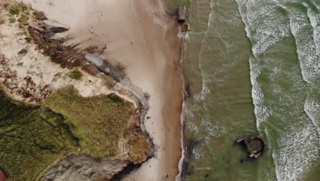 Vista-Aérea-De-Arriba-Hacia-Abajo-De-La-épica-Playa-De-Arena-Con-Viejos-Búnkeres-Alemanes-Tirados-En-La-Arena-Y-El-Agua-Mientras-Las-Olas-Anchas-Golpean-La-Playa