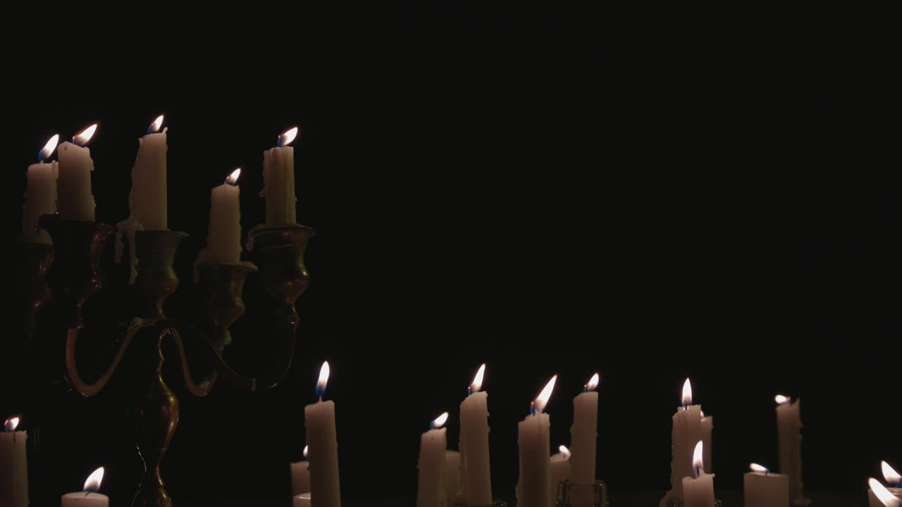 un grupo de velas blancas, algunas en un candelabro, encendidas y funcionando durante un tiempo