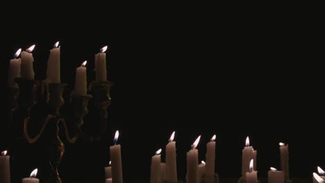 a group of white candles some on a candelabra lit up and running for a while