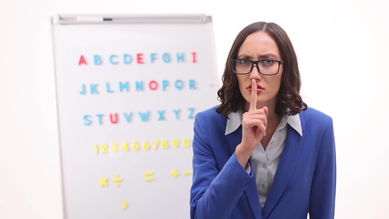 Professora exige silêncio com um gesto de shhh perto do quadro