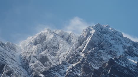 Rugged-Snowy-Mountains-with-beautiful-clouds-rolling-over-with-a-big-blue-sky