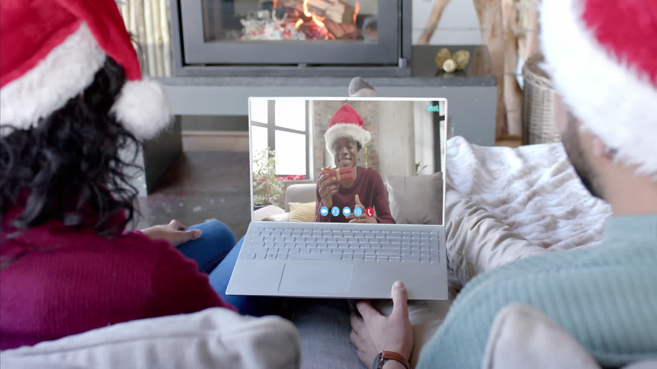 Coppia felice e un amico che fanno una videochiamata di Natale tramite laptop, al rallentatore