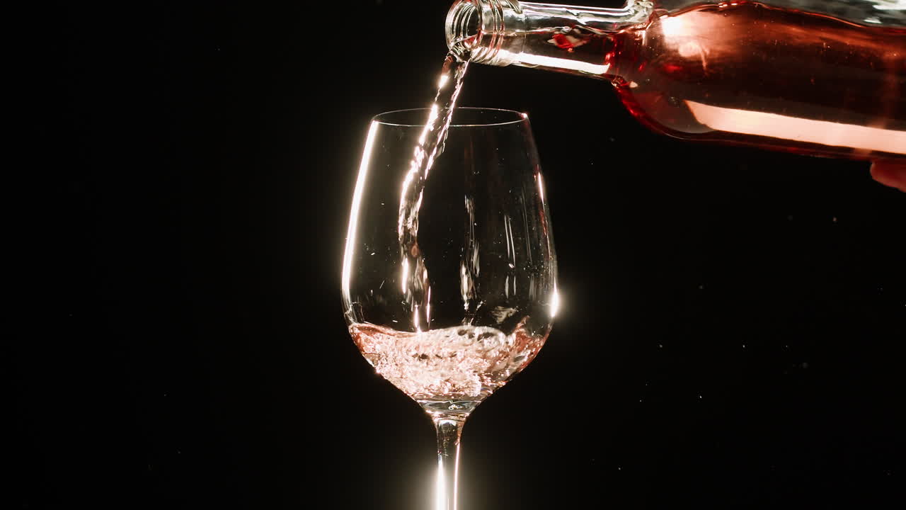 Rose Orange or white wine bottle and glass against a sunset in a peaceful vineyard, pouring of ecological natural wine. Cheers, hands with wine glasses, drinking alcohol.