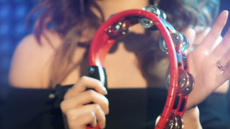 young woman is playing on the tambourine in studio