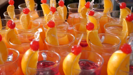 pan over a catering table of full of many fancy alcoholic cocktails with garnishes at a party