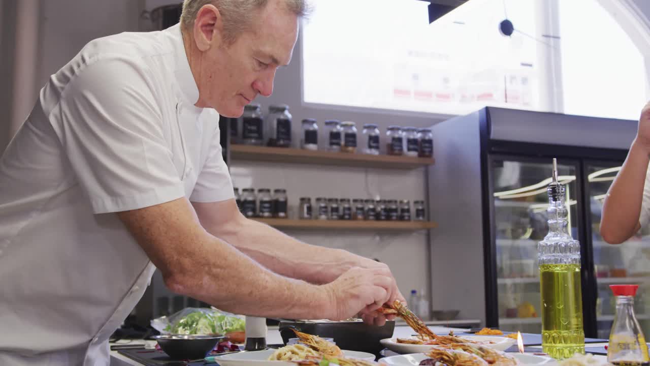 cocinero caucásico vestido de blanco en una cocina de un restaurante, poniendo comida en un plato
