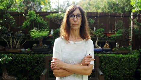 Mature-woman-standing-with-arms-crossed-in-the-garden-4k