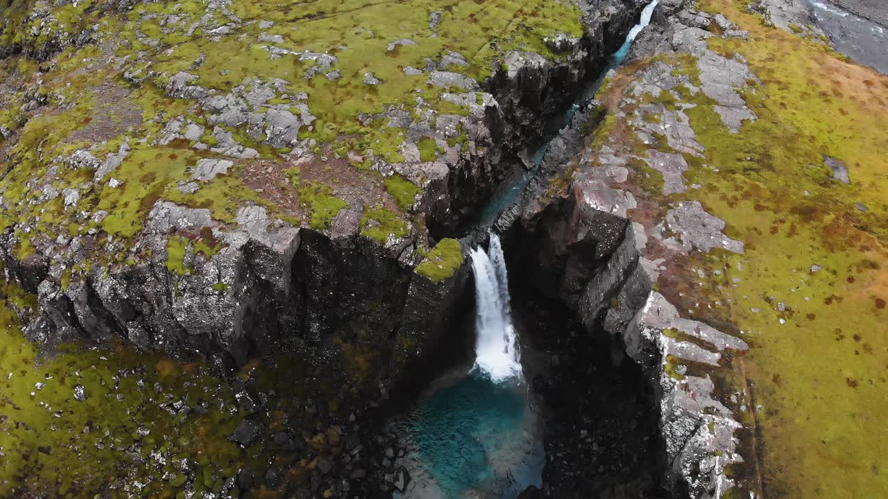 imágenes aéreas de las montañas de islandia que muestran una cascada grabada desde arriba y descendiendo