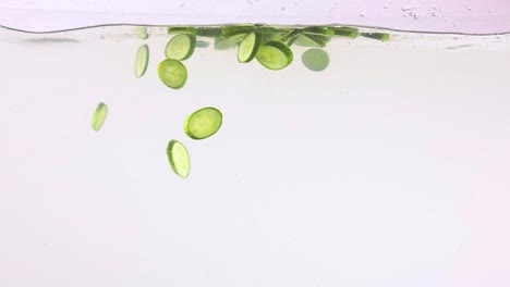 rebanadas de pepino cayendo en el agua