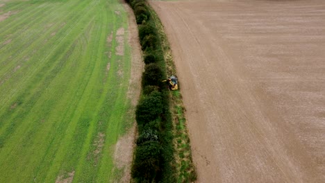 aerial view of hedge being trimmed by tractor in field