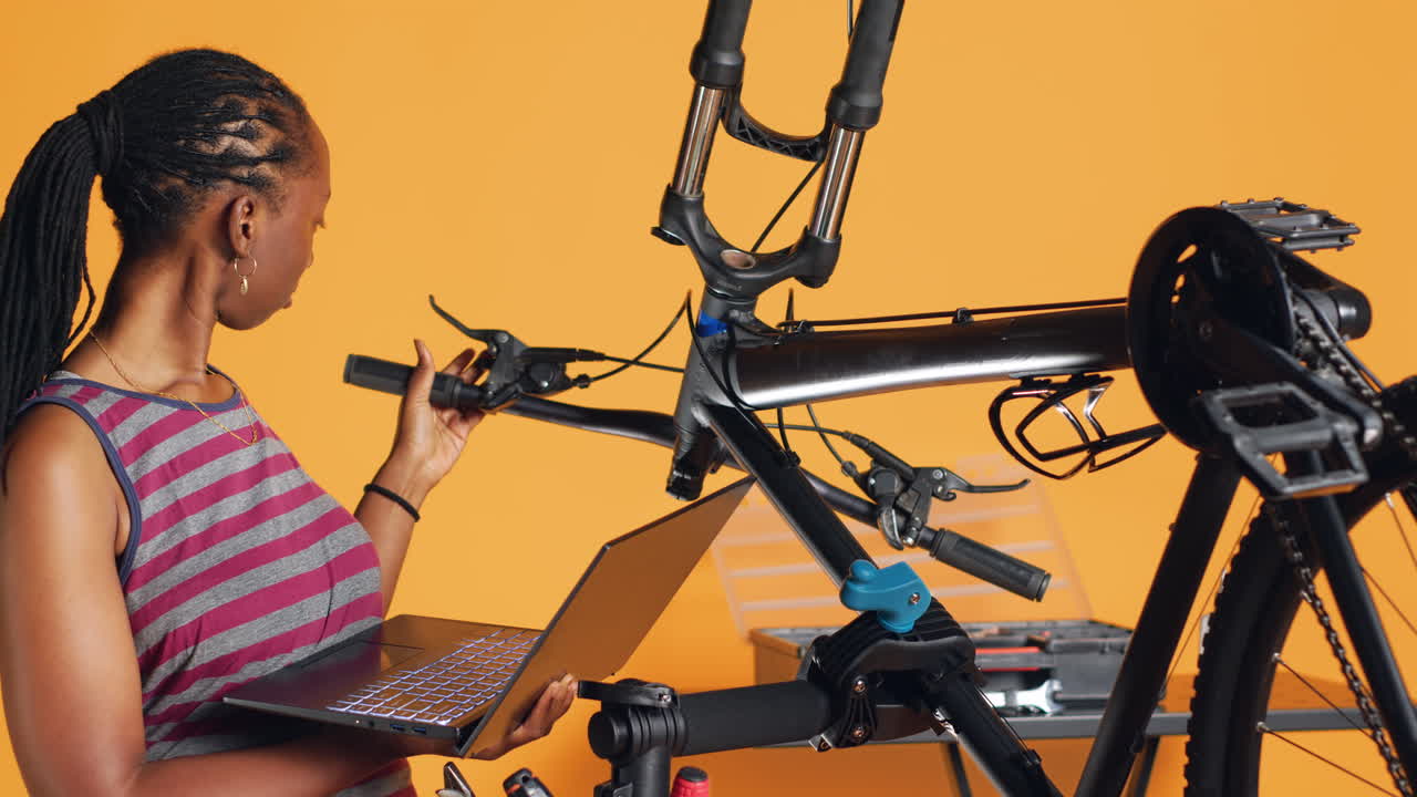 técnico con una computadora portátil en la mano analizando una bicicleta rota sobre el fondo del estudio