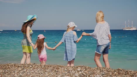 young girls with about their young children have fun on the coast, jump on the waves, enjoy the rest
