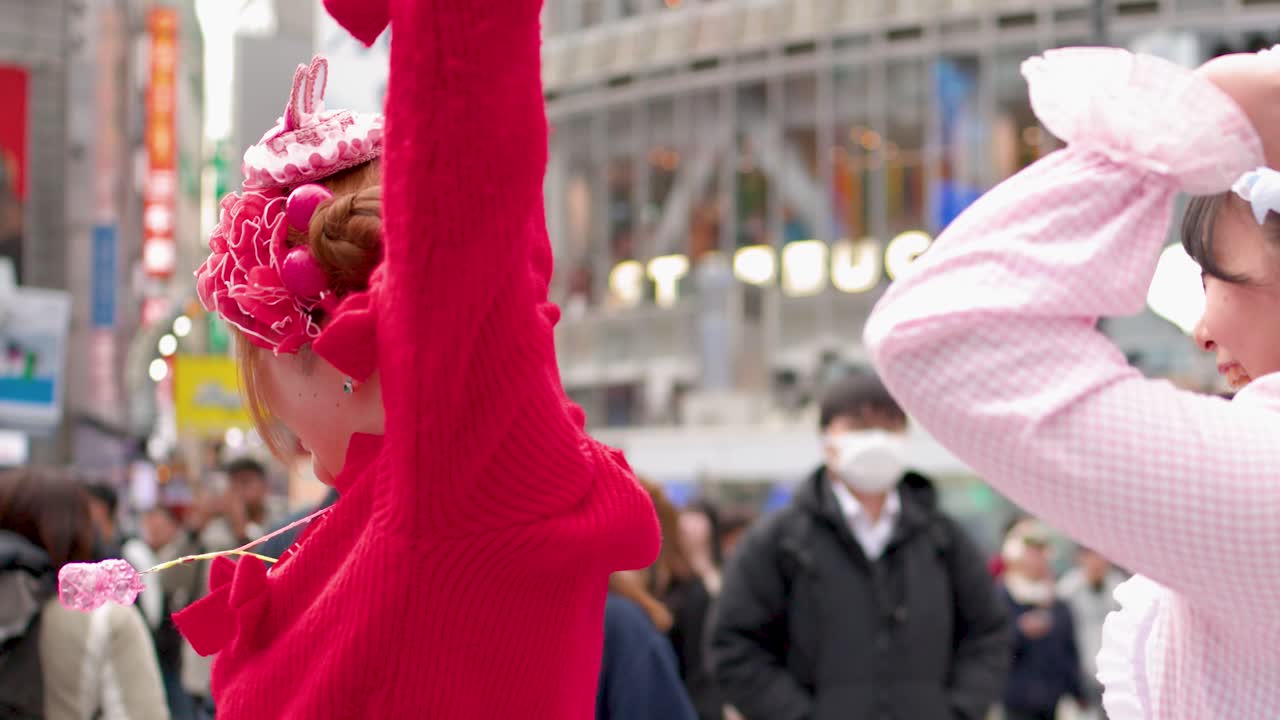 Two women in vibrant pink and red decora fashion laugh and cheer in Shibuya Tokyo