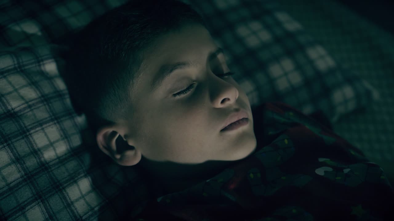 침대 위 에 있는 방 에서 밤 에 잠을 자는 아이