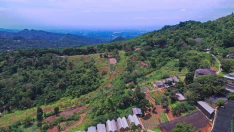 cinematic 4k aerial of agricultural fields and greenhouses nestled in tropical mountain hills, showcasing sustainable farming and rural life in the philippines