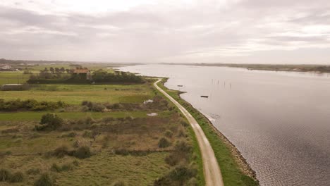 Vista-Aérea-De-4k-De-Un-Camino-Sucio-En-La-Cabecera-De-La-Ría-De-Aveiro-En-El-Estuario-Del-Río-Vouga,-Drone-Avanzando,-Silueta-De-Barco,-60fps