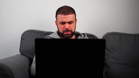 hombre caucásico del este medio pensando en serio mientras trabaja delante de la computadora portátil