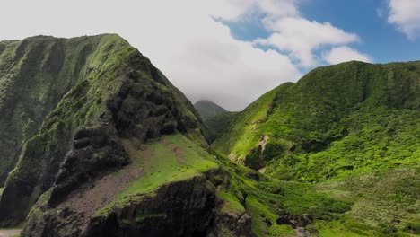 Toma-Aérea-De-Colinas-Verdes-Cubiertas-De-Plantas-Y-Musgo-En-La-Isla-De-Las-Orquídeas-Y-Nubes-Como-Telón-De-Fondo