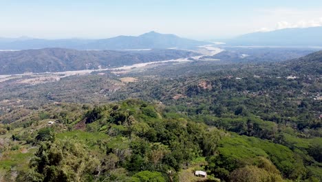 aerial rising over jesus christ statue, large river and mountain ranges in vast wilderness landscape in remote coffee district of ermera, timor leste, southeast asia