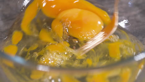 mixing eggs with a fork, making scrambled eggs in a glass bowl, mixing egg yolk and white