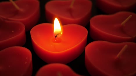 one lit heart shaped candle amongst group of unlit candles seamlessly looping conceptual video background