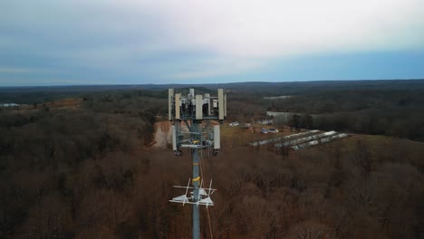 aerial shot rotating around cell phone tower with forest in background. 4k drone