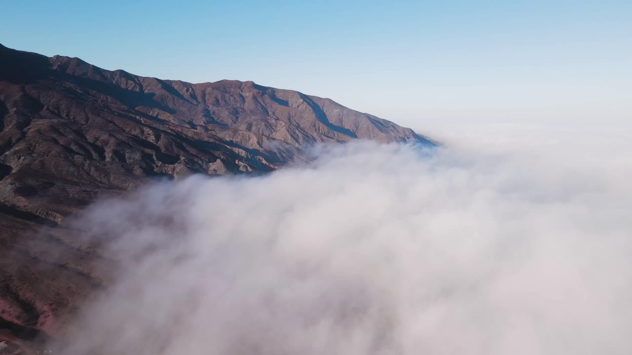 Misty mountain ridges at Cedros Island during sunrise, dramatic view of soft clouds rolling over terrain, aerial ascend