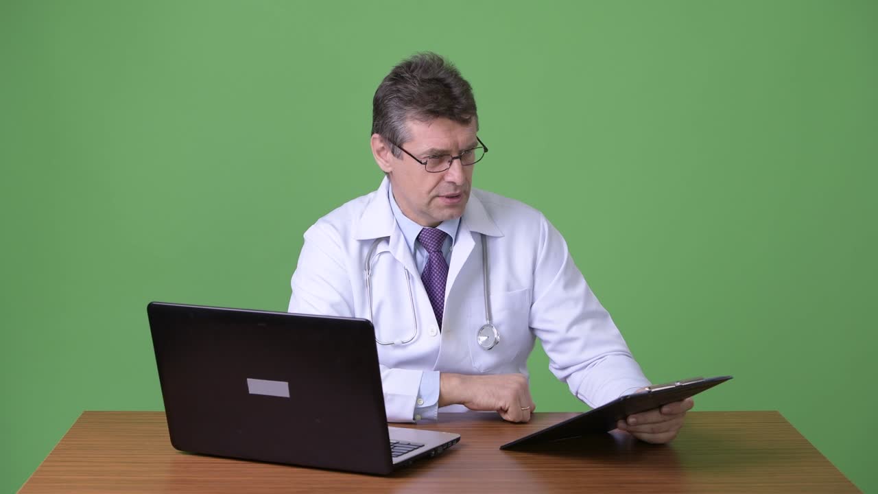 hombre maduro y guapo médico contra fondo verde