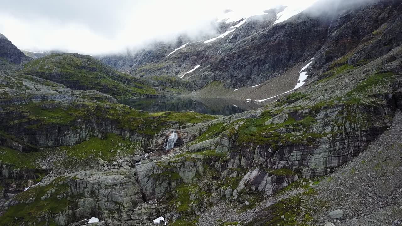Flyr over naturen i de norske fjellene, nærmer seg en vakker innsjø og foss