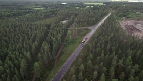 aerial bird view of forest road in finland, car porter truck passing by, car transportation, countryside, traffic, summer, overcast day