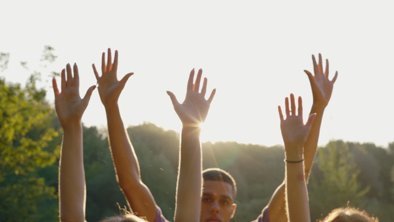 Group of people raising hands in sunlight
