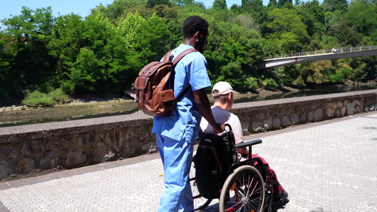 Assistente che spinge un giovane in sedia a rotelle lungo la riva del fiume