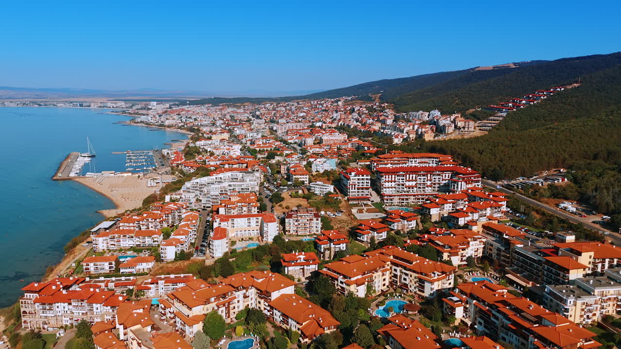 Diversi hotel con tetti rossi e molteplici piscine sui pendii verdi delle montagne. Filmato aereo sopra il Mar Nero a Sveti Vlas, Bulgaria.