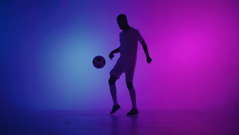 Schwarzer-Mann,-Ein-Spieler-Jongliert-Mit-Fußball-In-Einem-Dunklen-Studio-Mit-Neonlichtern-Auf-Dem-Boden-Und-Roten-Und-Blauen-Lichteffekten-In-Zeitlupe.-Afrikanischer-Fußballprofi